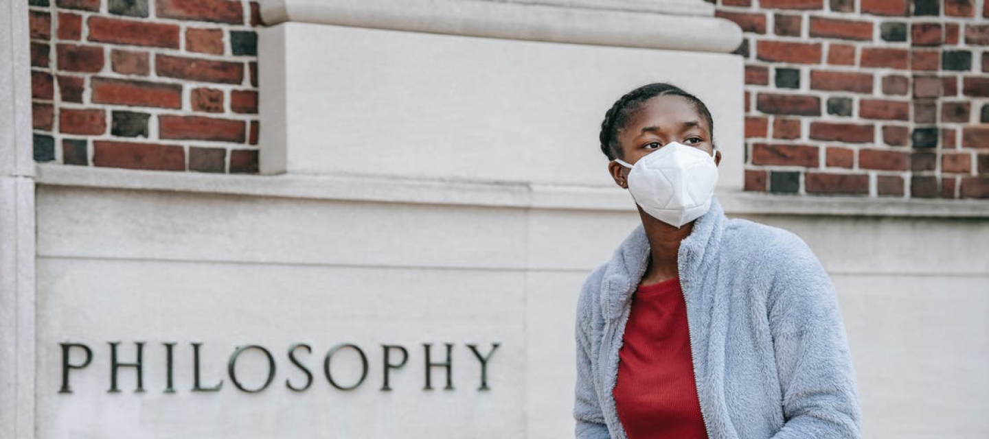 Student with N95 mask holds laptop